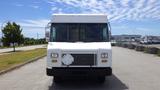 A white 2011 Ford Econoline with a flat front and slatted grill parked on a road