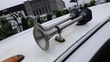 A pair of silver air horns mounted on the roof of a white 2008 Chevrolet C7500