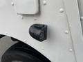 A black side marker light mounted on the fender of a 2005 Freightliner MT45 Chassis with a raindrop-covered surface