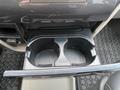 A black cup holder with a divider designed to hold two cups inside a 2013 Toyota Sienna's center console