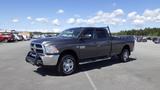 A gray 2014 RAM 3500 truck with a crew cab and chrome accents parked on a lot with a black grille guard and chrome wheels