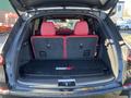 A 2023 Acura MDX with red leather seats and a spacious cargo area featuring a black rubber mat and rear seats in an upright position