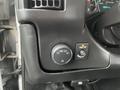 Control panel of a 2017 Chevrolet Express featuring a dial for headlight settings and two buttons for interior lighting and a button for turning lights off