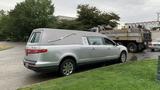 A 2013 Lincoln MKT hearse with a gray top parked beside a gravel road