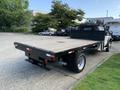 A 2013 Ford F-450 SD flatbed truck with a wooden bed and a black metal frame viewed from the rear angle