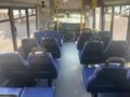 Interior view of a 2017 Chevrolet Express bus with blue seats arranged in rows and a driver's area at the front