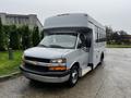 2015 Chevrolet Express bus with a gray exterior and a large windshield parked with doors closed