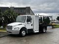 A 2005 Freightliner M2 106 truck with a white cab and black flatbed, equipped with storage compartments and mounted equipment on the flatbed