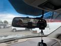 Interior view of a rearview mirror in a 2010 Dodge Ram with a hand holding the mirror and a device attached to it