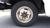 A close-up of a wheel on a 2011 Ford Econoline showing a white steel rim with five lug nuts and a worn black tire