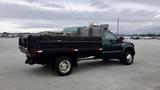 A green 2008 Ford F-450 Super Duty truck with a flatbed and dual rear wheels parked on a concrete surface