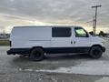 A white 2001 Ford Econoline van with black accents and black wheels parked on a gravel surface