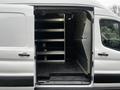 Interior view of a 2021 Ford Transit van showing open doors shelves along the side and a cargo space with a rubber floor mat