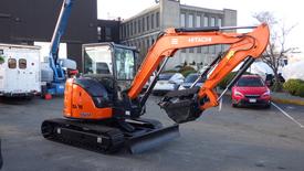 A 2021 Hitachi 55USR excavator with an orange arm and bucket on a black track base positioned for operation