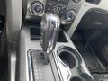 Interior view of a 2014 Ford F-150 gear shifter with a chrome knob and surrounding controls for air conditioning and audio system