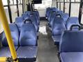 Interior view of a 2017 Chevrolet Express with rows of blue seats and yellow handrails