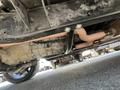 View of the underside of a 1962 Ford F-100 showcasing the transmission and exhaust system with visible metal components and pipes