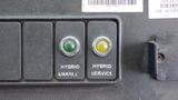 Dashboard buttons labeled "HYBRID ENABLE" with a green indicator and "HYBRID SERVICE" with a yellow indicator on a control panel