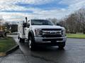 A 2017 Ford F-550 truck with a utility box and orange safety lights on the roof parked on a paved surface