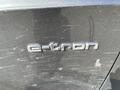 A close-up view of the e-tron badge on a black Audi A3 showing surface scratches and dust on the car's exterior