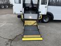 A 2017 Chevrolet Express with a lowered wheelchair ramp positioned at the rear entrance showcasing a black and yellow surface with handrails