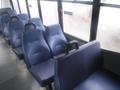 Interior view of a bus with blue vinyl seats arranged in rows with handholds on the sides