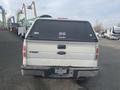 A white 2009 Ford F-150 truck viewed from the rear featuring a black cover over the bed and bumper stickers on the back window