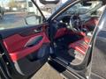 Interior view of a 2023 Acura MDX featuring red leather seats and red accents on the door and dashboard with a steering wheel and gear shift visible