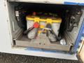 A yellow and gray battery mounted in a compartment of a 2017 Chevrolet Express with visible electrical connections and components