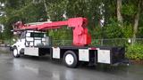 A white 2010 International 4300 truck with a flatbed and a red aerial lift mounted on the back