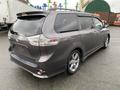 A grey 2013 Toyota Sienna minivan parked with a sleek design and alloy wheels showcasing its rear and side profile