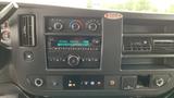 Dashboard of a 2017 Chevrolet Express Quigley 4x4 featuring controls for climate and audio systems with digital displays and various buttons