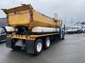 A yellow 2016 International 7400 truck with a large dump bed and dual rear wheels parked with its back facing the camera