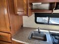 A 2012 Ford Econoline interior featuring wooden cabinetry a countertop and a stainless steel sink