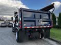 A blue 2011 International 7300 truck with a raised dump bed and visible tail lights parked in a lot