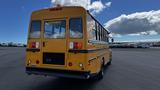 A yellow 2014 Freightliner Thomas Diesel bus with a rear entrance and multiple lights on top and sides