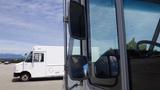 A 2011 Ford Econoline van is parked with its side mirror visible and another vehicle in the background