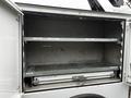 An empty storage compartment of a 2015 Ford F-550 with metal shelves and sliding drawers