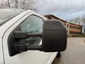 A white 2017 Ford F-350 SD with a side mirror showing raindrops on the glass