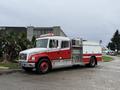 A red and white 2001 Freightliner FL80 fire truck with equipment storage compartments and a light bar on the roof