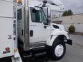 A white 2009 International 7400 truck with a utility body and a lift bucket attached on the driver's side