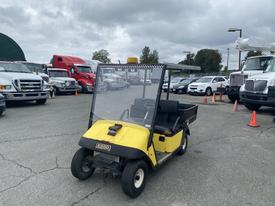 A yellow 2000 EZ-GO Industrial 800 golf cart with a transparent enclosure and a black seat in the foreground