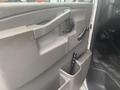 Interior view of a 2017 Chevrolet Express showing the driver's side door panel with a handle storage compartment and a black object in the cup holder