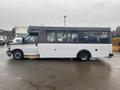 A 2018 Chevrolet Express bus with a white body and dark roof featuring large windows on the side and a passenger door at the front