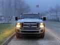 A 2015 Ford F-550 truck is facing forward with its headlights on and several roof lights illuminated