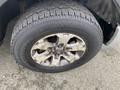 A close-up view of a 2014 Ford F-150 tire mounted on a rim with a rugged tread pattern and some visible dirt on the wheel surface