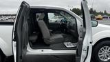 A 2016 Nissan Frontier with its front door open revealing the interior seats and dashboard