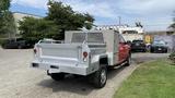 A red 2013 RAM 2500 truck with a silver utility bed and storage compartments on the back