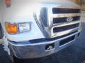 A 2006 Ford F-650 truck with a shiny chrome front grille and headlights in the foreground