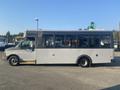 A silver 2017 Chevrolet Express bus with large windows and a low floor design parked in a lot